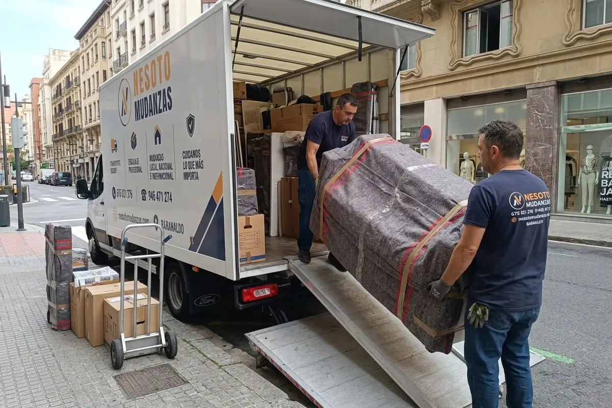 Operarios de NESOTO cargando cajas y muebles protegidos en el camión de mudanzas