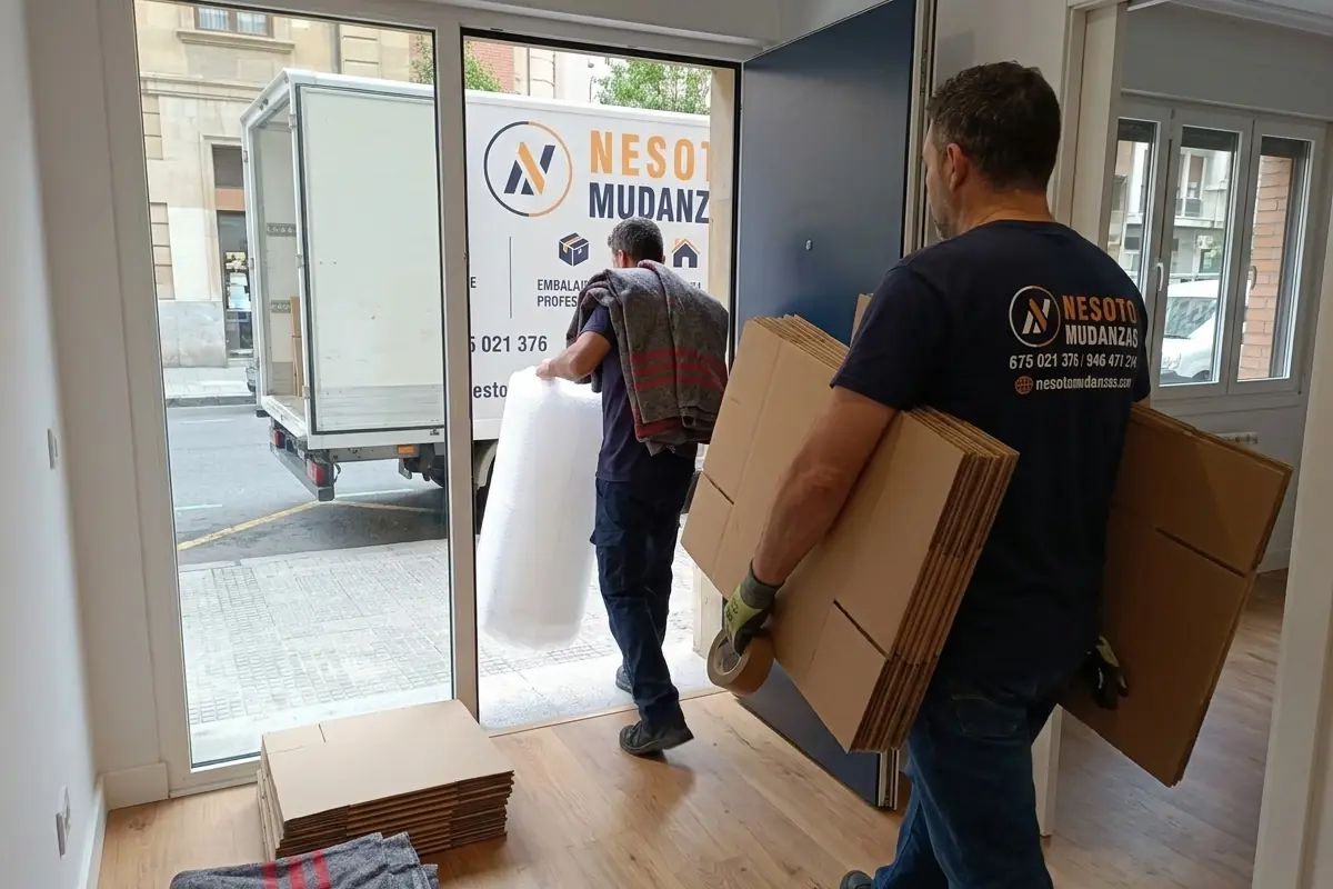 Operarios de NESOTO llevando cajas, plástico de burbuja y mantas a una vivienda para el embalaje