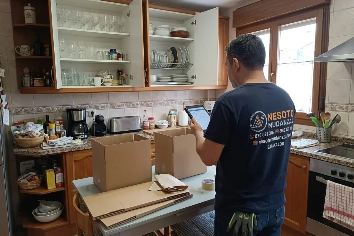Operario de NESOTO valorando con una tablet el menaje y la vajilla de una cocina que hay que embalar