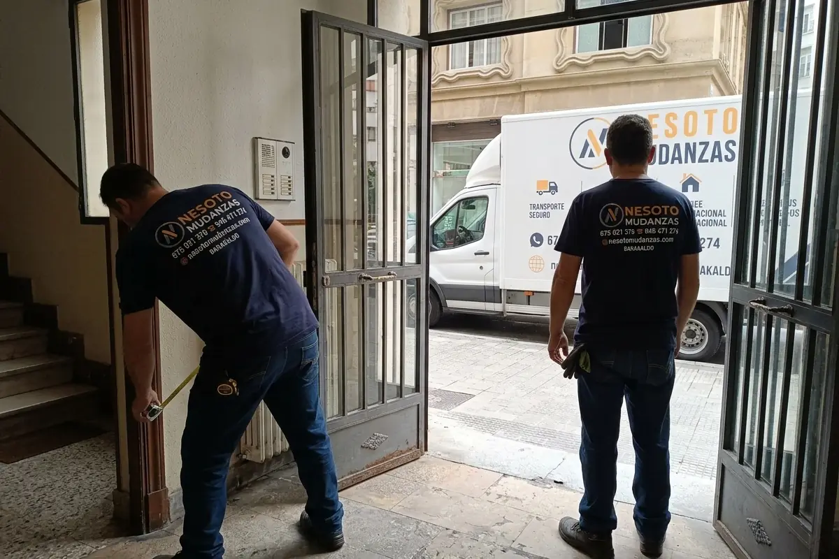 Operario de NESOTO midiendo el portal de un edificio con el camión de mudanzas aparcado en la calle