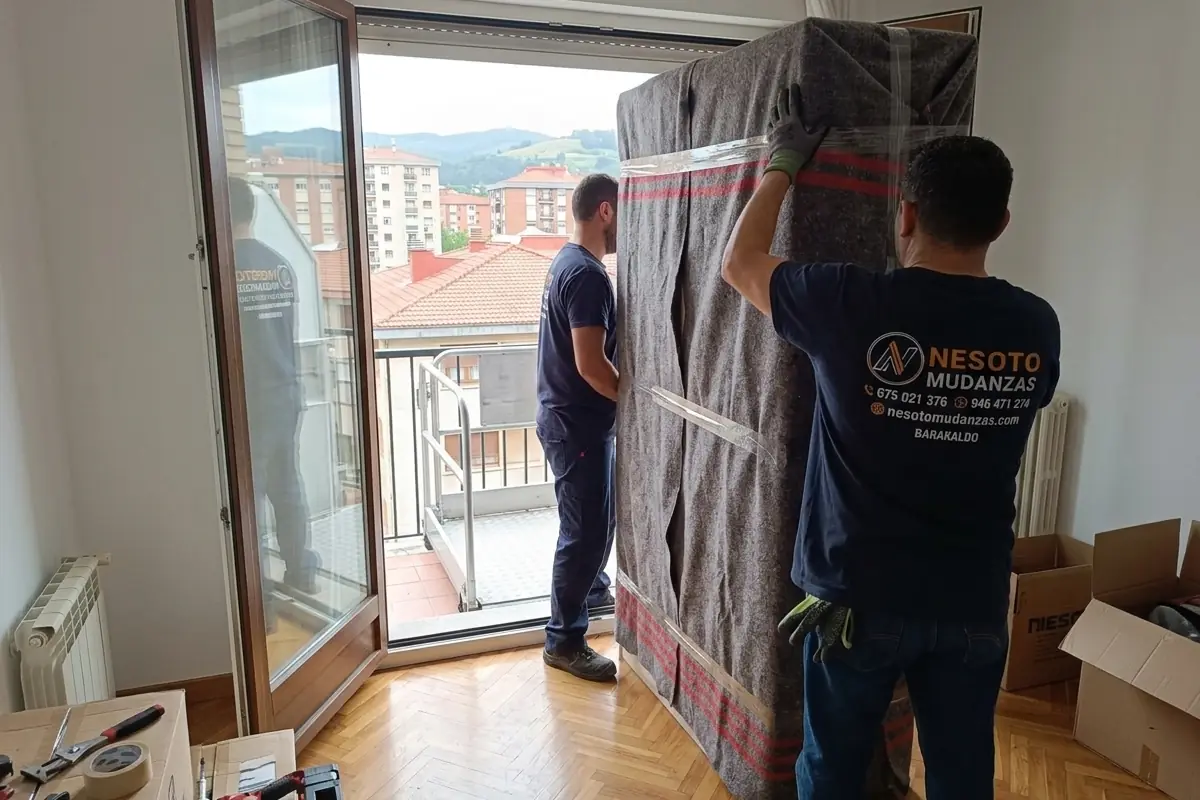 Operarios de NESOTO recibiendo un armario protegido por el balcón de un piso