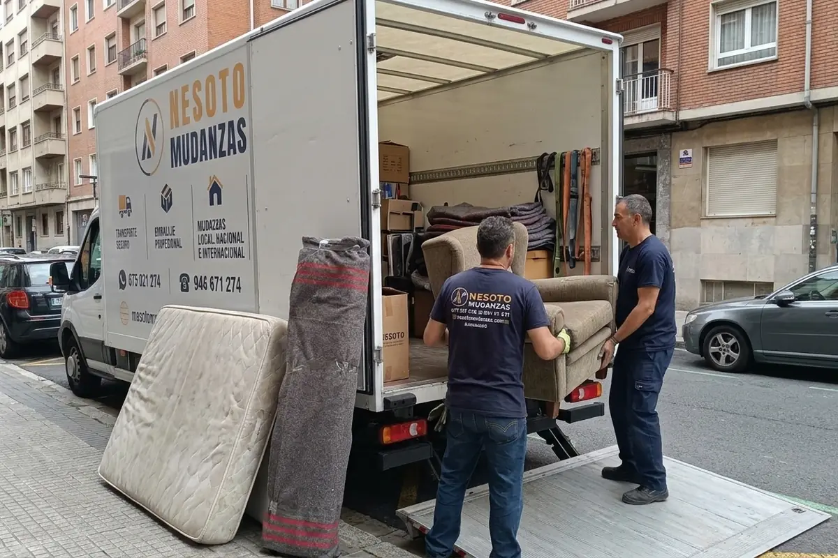 Operarios de NESOTO cargando un colchón, un sillón y muebles en el camión durante el vaciado de un piso